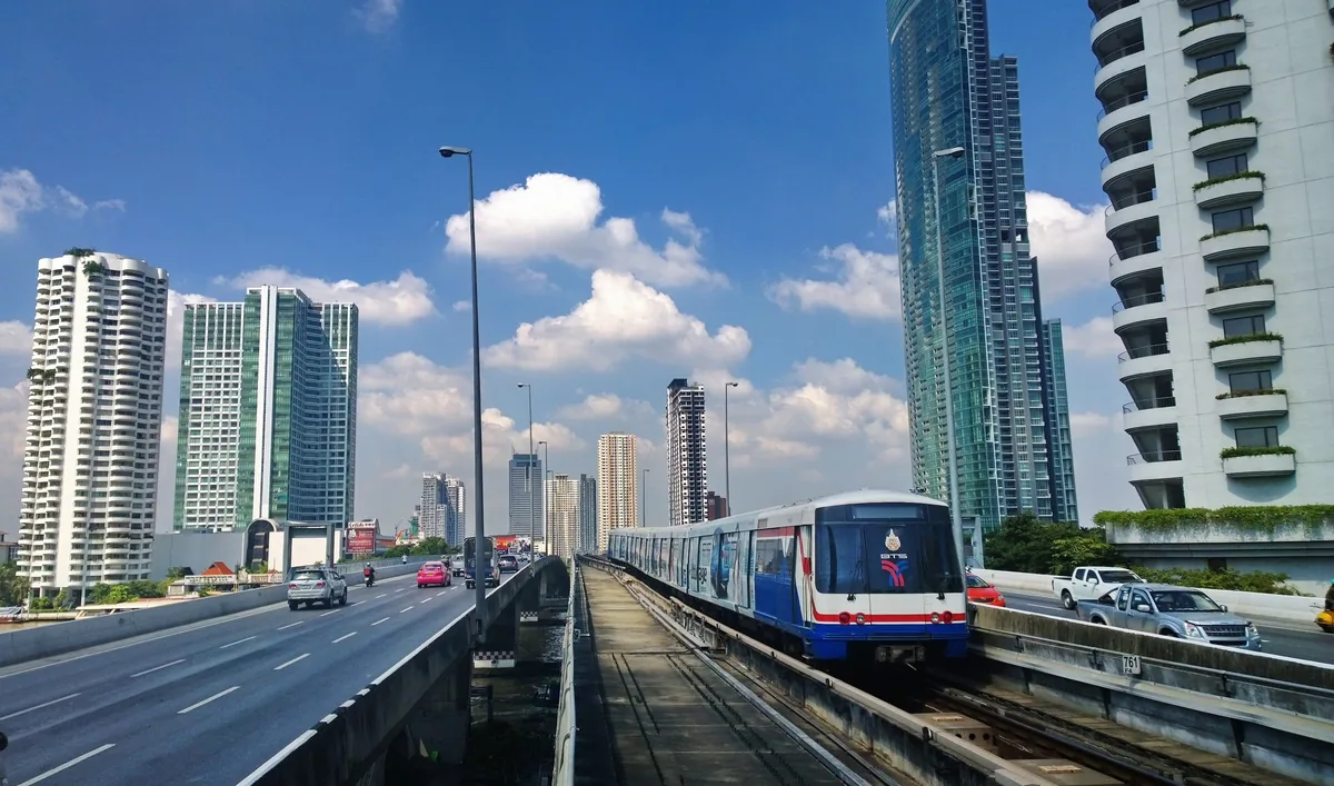 An elevated BTS Skytrain runs between busy roads flanked by high-rise towers in Bangkok.
