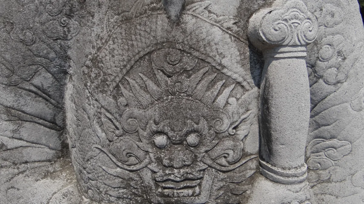 Close-up of an intricately carved stone dragon motif on a royal tomb sculpture in Hue