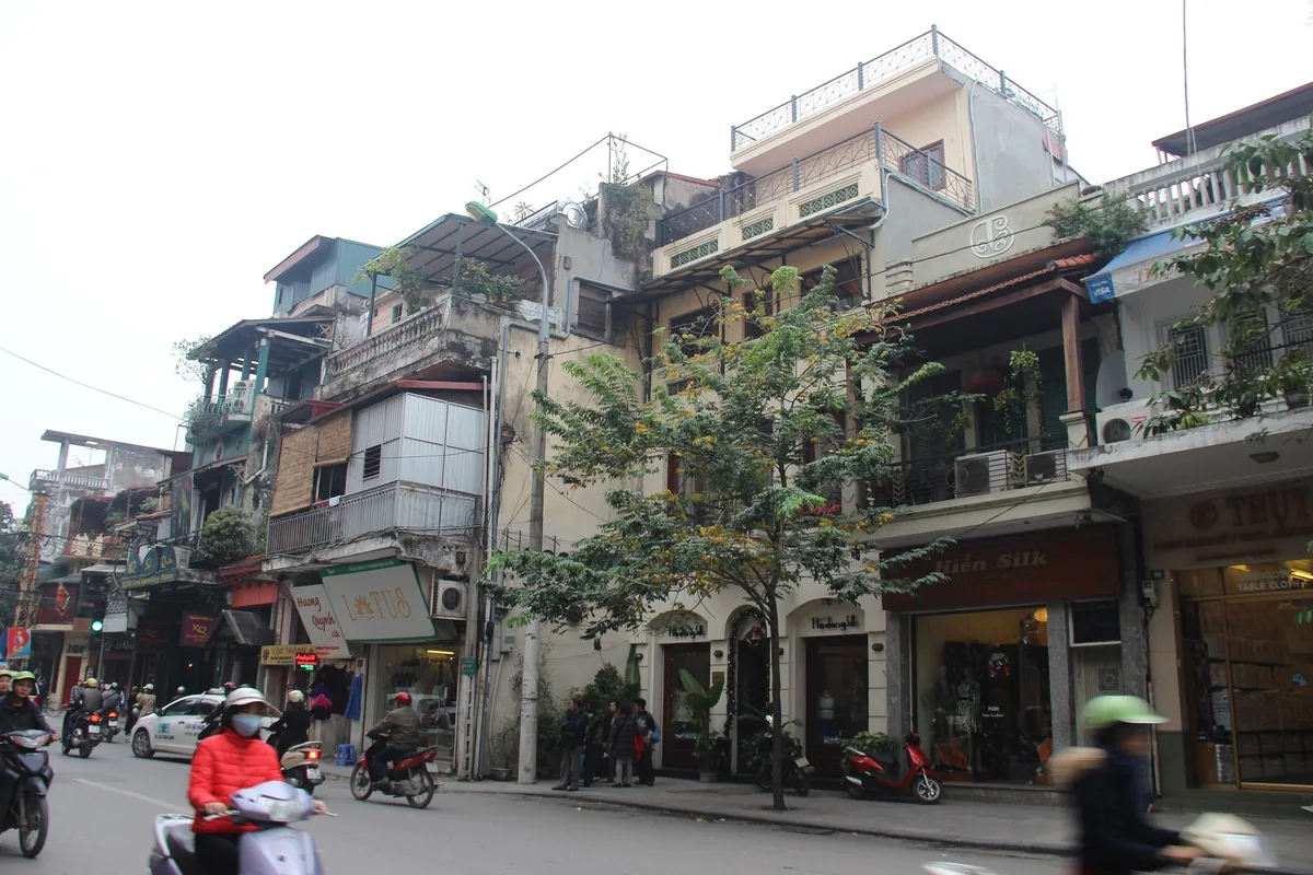 Motorbikes pass narrow tube houses and shops along Hang Gai Street in Hanoi's Old Quarter.