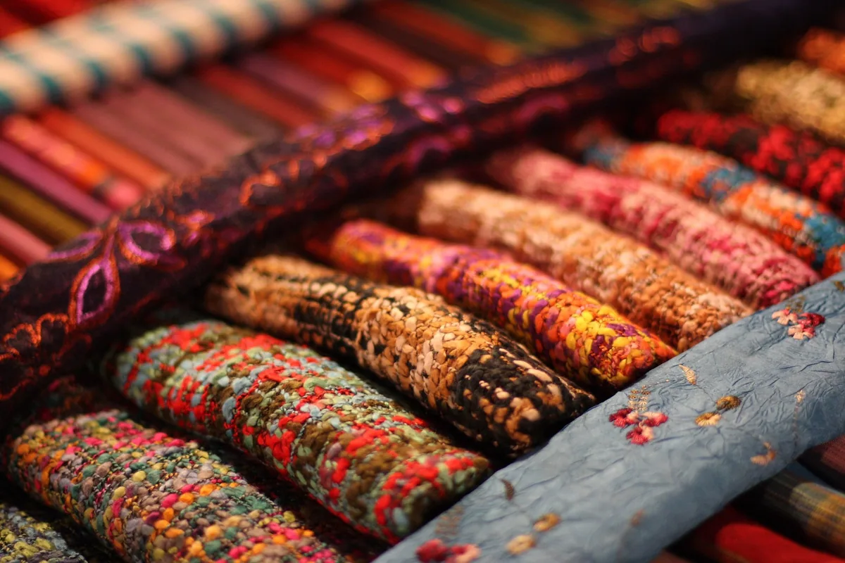Rolled colorful woven textiles on display at a Hmong market stall in Luang Prabang, Laos.