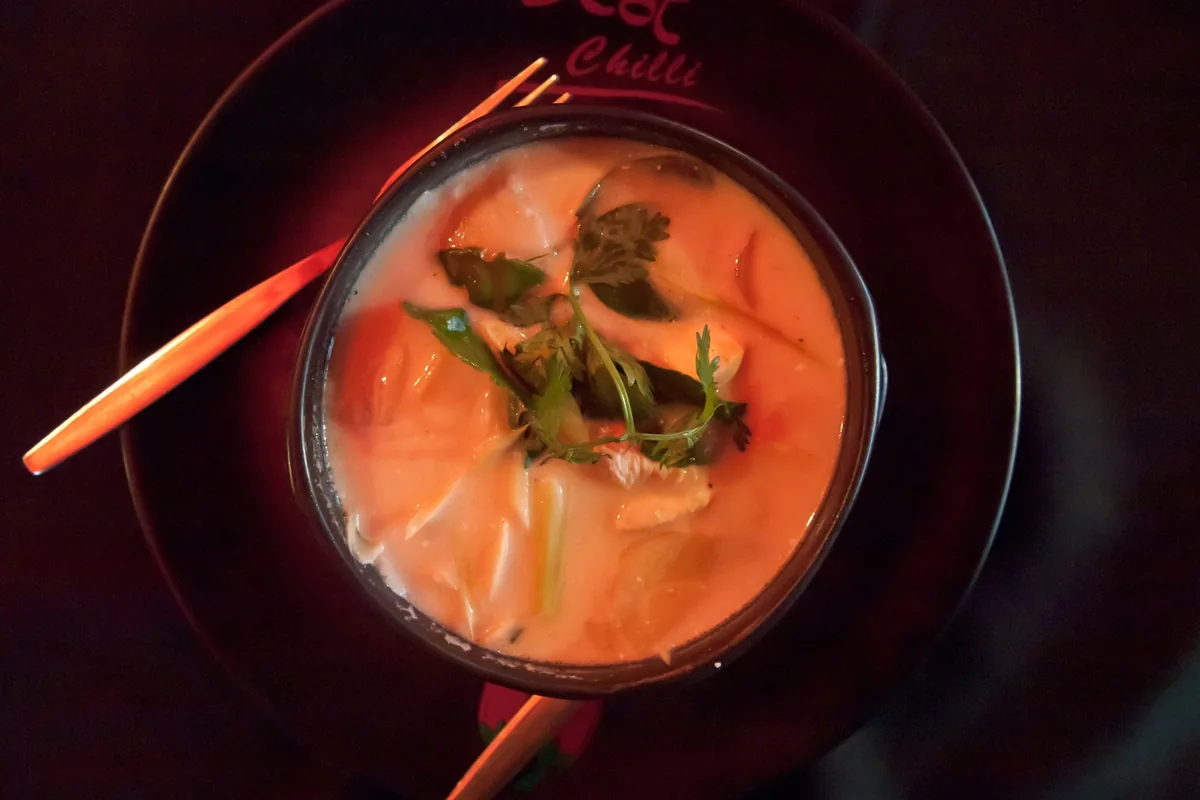 A bowl of creamy tom kha coconut soup garnished with herbs, served at a restaurant in Chiang Mai.