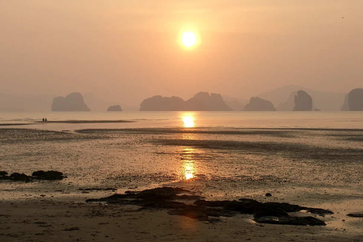 Sunrise glows over limestone karst islands and low-tide flats in Phang Nga Bay, Khao Lak.