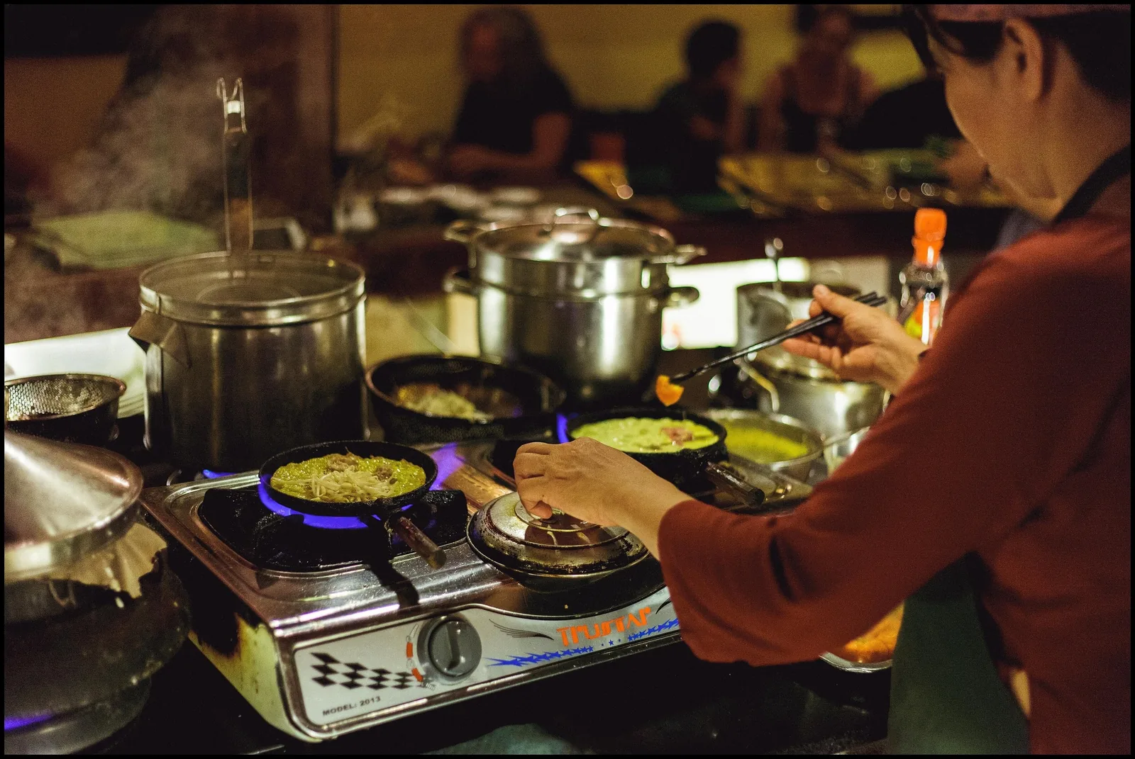 A cook prepares Vietnamese pancakes on gas burners at an open kitchen in Hoi An.