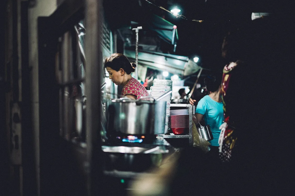 A street food vendor cooks over a pot at a night stall in Ho Chi Minh City.